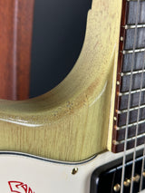 Close-up of a guitar's neck and headstock with a brand logo.