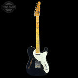 Electric guitar with a black body and white pickguard on a black background, featuring the Tone Shop logo.
