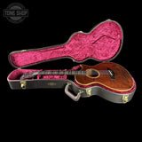 Acoustic guitar in a pink-lined case with 'Tone Shop' logo.