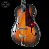 Vintage mandolin with a dark brown finish on a black background, featuring the Tone Shop logo.