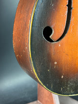 Close-up of a wooden instrument with a sound hole on a dark background