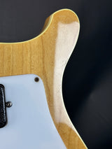 Close-up of a guitar's wooden neck and white pickguard on a dark background