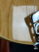 Close-up of a guitar's bridge and part of its neck on a wooden surface.