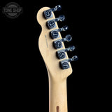 Close-up of the headstock of a Fender electric guitar in a natural maple finish, featuring six black tuning pegs with silver rings, set against a solid black background.