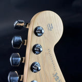 Close-up of a guitar headstock with tuning pegs on a dark background