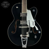 A black Gretsch hollow-body electric guitar with a white pickguard, chrome hardware, and a silver Tremolo tailpiece, shown against a solid black background.