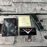 Fender Custom Stratocaster guitar accessories arranged in a plush gray case, including a black leather pickguard with red Fender logo, a black guitar strap, a certificate, a branded card, and a small badge.