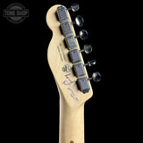 Close-up rear view of a guitar headstock with six black tuning pegs and silver tuning keys on a light natural wood neck, shown against a black background. A Tone Shop watermark is visible in the top left corner.