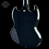 The rear view of a glossy black electric guitar against a solid black background, featuring a chrome trim line and a gold-toned screw cap.