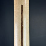Close-up of a wooden object showing a light natural wood grain surface with a vertical dark brown wood inlay slot, set against a dark gray background.