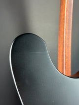 Close-up of a guitar neck and headstock with a dark finish and wooden fretboard.