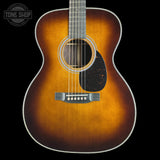 A classic acoustic guitar with a natural sunburst finish, shown from the front against a solid black background. The brand logo 'TONE SHOP' is visible as an overlay in the top-left corner.