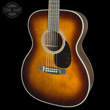 A close-up of a classic acoustic guitar body showing a natural wood sunburst finish that fades from bright amber-orange in the center to dark brown at the edges, set against a solid black background.