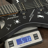 Black electric guitar with white designs on a digital scale displaying weight.