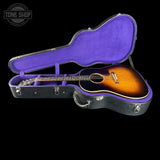 Acoustic guitar in an open case with a visible brand logo on a black background
