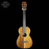 A classical acoustic guitar with a beautiful flame maple wood top, shown vertically against a solid black background. The Tone Shop logo is visible in the top-left corner.