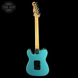Turquoise electric guitar with a wooden neck on a black background, featuring 'Tone Shop' branding.