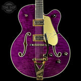 Purple electric guitar with gold hardware on a black background, featuring the Tone Shop logo.