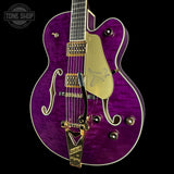 Purple electric guitar with gold hardware on a black background, featuring 'Tone Shop' logo.