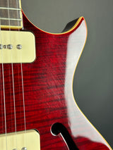 Close-up of a red electric guitar with a white pickguard on a dark background