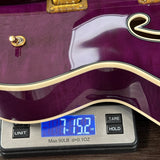 Purple electric guitar on a digital scale displaying weight.