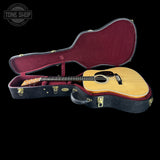Acoustic guitar in an open case with 'Tone Shop' logo.