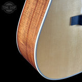 Close-up of an acoustic guitar's soundhole and body on a black background with 'Tone Shop' logo.