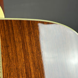 Close-up detail of an acoustic guitar body showing a rich dark brown wood grain section on the left and a glossy light-colored backplate on the right, separated by a gold-toned binding line.