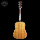 Back view of a wooden acoustic guitar on a black background with 'Tone Shop' logo.