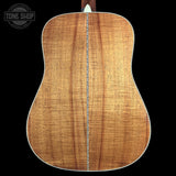 Back view of a wooden acoustic guitar with 'Tone Shop' logo in the corner.