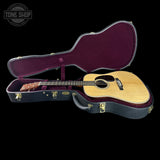 Acoustic guitar in an open case with 'Tone Shop' branding.