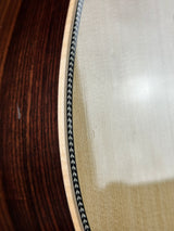 Close-up of a guitar's soundhole with a white pickguard and black binding.