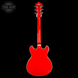 A bright red electric guitar shown from the back against a solid black background, with a Tone Shop watermark in the upper left corner.