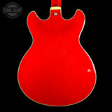 The back of a red electric guitar with a glossy red finish and a white binding edge, shown against a solid black background. A Tone Shop watermark is visible in the top left corner.
