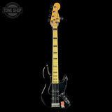 A black electric bass guitar with a natural wood neck and headstock, shown vertically against a solid black background. A Tone Shop watermark is visible in the top-left corner.