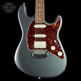 Electric guitar with a flame maple top on a black background, featuring the Tone Shop logo.