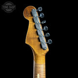 Close-up of the headstock of a Fender electric guitar, showing the maple wood neck, six silver tuning pegs, and a vintage-style scalloped edge on a black background.