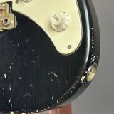 Close-up of a guitar's control knob and headstock with a black finish.