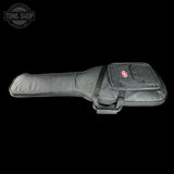 A black padded guitar or bass gig bag with a front zippered pocket featuring a red and white logo, shown against a solid black background. A Tone Shop watermark is visible in the top-left corner.