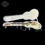 An open black guitar hard case on a black background, containing a cream-colored electric guitar with gold hardware. A Tone Shop watermark is visible in the top-left corner.