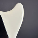 Close-up of a glossy off-white electric guitar body corner against a dark gray background.