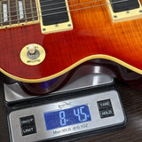 Gibson Les Paul guitar on a digital scale displaying weight.