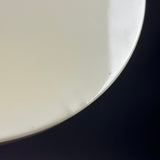 A close-up of a glossy off-white ceramic plate or dish edge against a dark navy background.