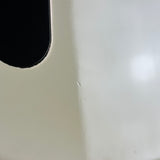 Close-up of a glossy off-white appliance surface with a black rounded cutout in the upper left and a soft light reflection on the right.