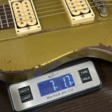 Gold electric guitar on a digital scale displaying weight