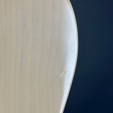 Close-up of a curved white surfboard edge with a small visible scratch on the deck, set against a dark navy blue background.