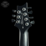 Close-up rear view of a guitar headstock in black with six silver tuning pegs and white printed specifications, shown against a black background. A Tone Shop watermark appears in the upper left.