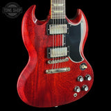 Red electric guitar with a black pickguard on a black background, featuring the Tone Shop logo.