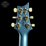 Close-up of a blue guitar headstock with tuning pegs on a black background, featuring 'Tone Shop' branding.