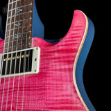 Close-up of a pink electric guitar with a blue pickguard on a black background